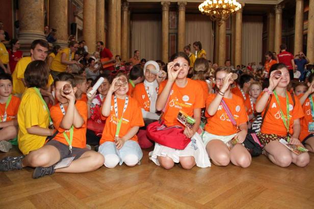 Eine Gruppe Kinder blickt durch Pappröhren in die Kamera.