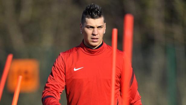 Ein Mann mit Irokesenschnitt trägt ein rotes Sporttrikot mit Nike-Logo.