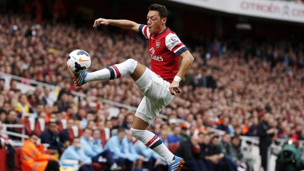Mesut Özil spielt einen Fußball vor einer Zuschauermenge.
