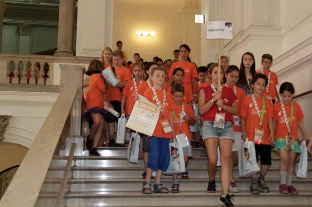 Eine Gruppe Kinder in orangefarbenen T-Shirts geht eine Treppe hinunter.