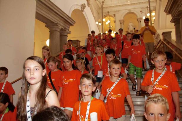 Eine Gruppe Kinder in orangefarbenen T-Shirts steht auf einer Treppe.
