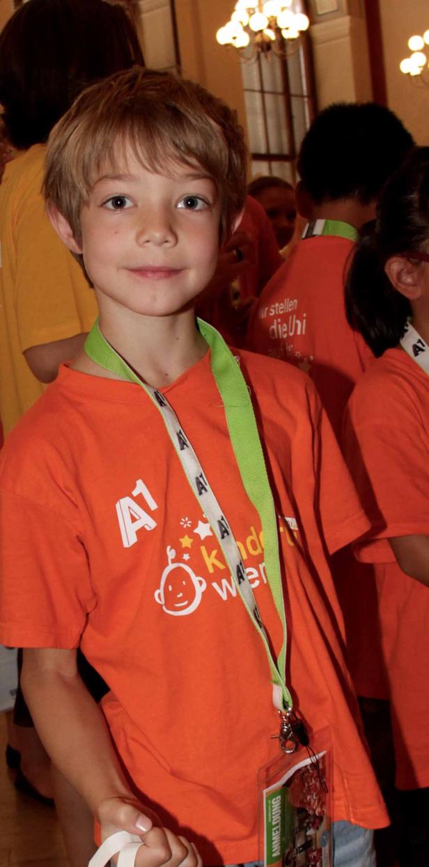 Ein junger Junge mit einem orangefarbenen T-Shirt und einem Namensschild um den Hals.