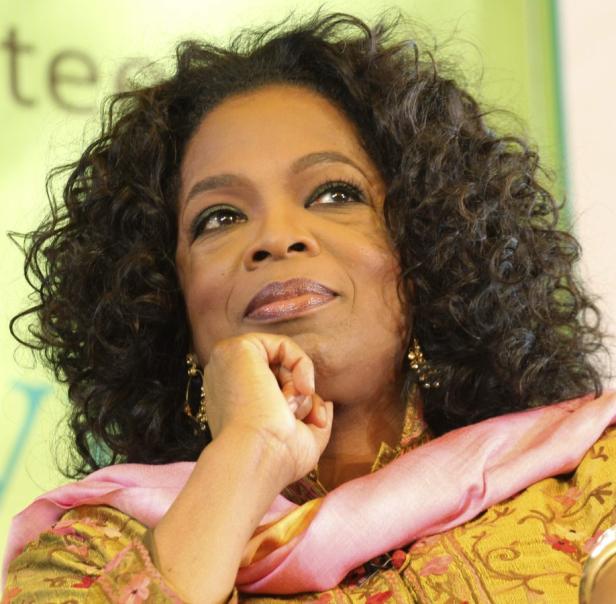 Oprah Winfrey blickt mit ihrer Hand am Kinn nach oben.