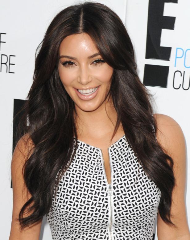 Kim Kardashian lächelt in einem gemusterten Kleid.