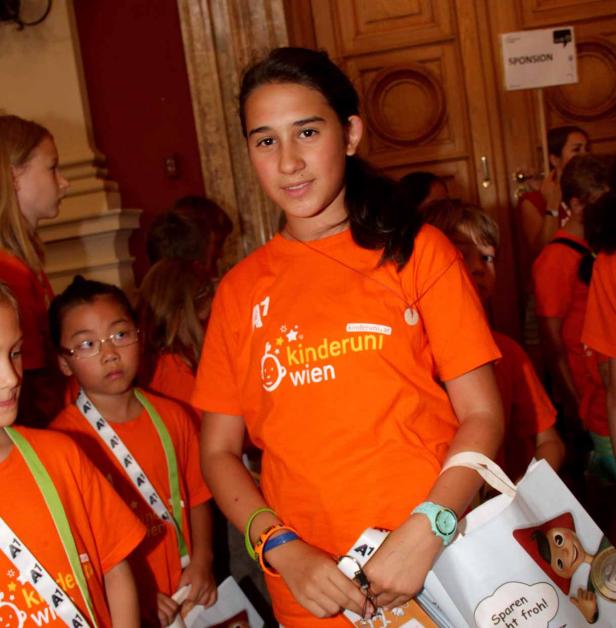 Ein Mädchen in einem orangefarbenen T-Shirt der Kinderuni Wien.