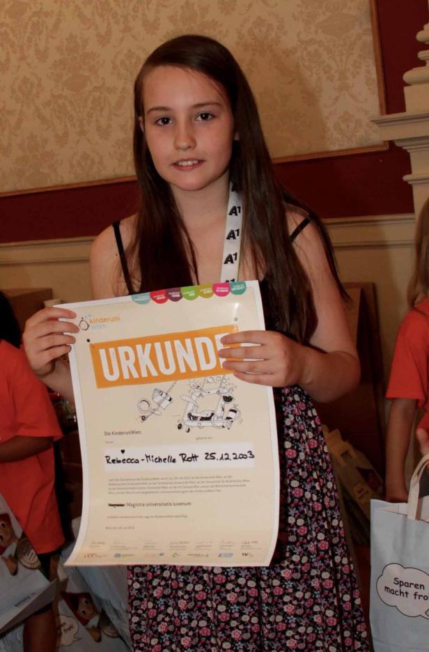 Ein Mädchen hält eine Urkunde der Kinderuni Wien in den Händen.