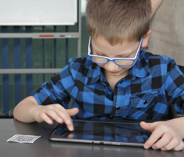 Ein Junge mit Brille bedient ein Tablet.