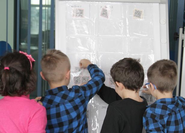Kinder ordnen QR-Codes auf einer Whiteboard-Tafel an.
