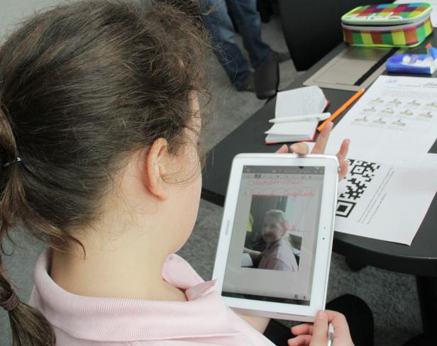 Ein Mädchen betrachtet ein Tablet, das einen Stundenplan und ein Foto eines anderen Mädchens zeigt.