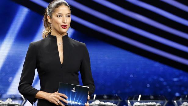 Eine Frau im schwarzen Blazer hält ein Buch der UEFA Champions League in ihren Händen.