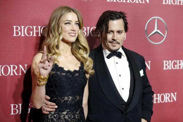 Amber Heard und Johnny Depp posieren auf einer Veranstaltung vor einem roten Hintergrund.