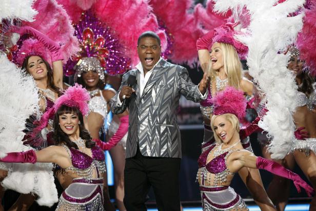Tracy Morgan steht mit Tänzerinnen in aufwendigen Kostümen auf einer Bühne.