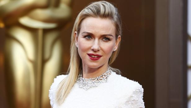 Naomi Watts trägt ein weißes Kleid und eine Halskette bei einer Preisverleihung.