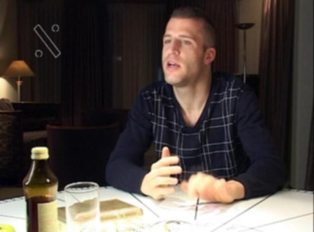 Ein Mann sitzt an einem Tisch mit einer Flasche und einem Glas Wasser.