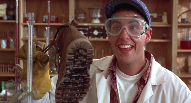Adam Sandler als verrückter Wissenschaftler mit Schutzbrille und einem Stiefel in der Hand.