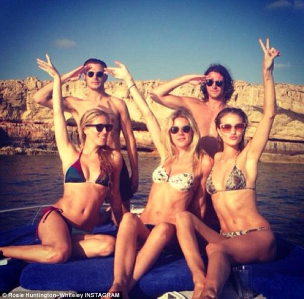 Rosie Huntington-Whiteley mit Freunden auf einem Boot, posierend vor einer Felsküste.