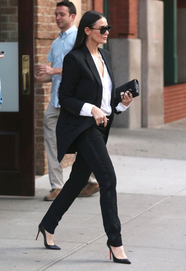 Demi Moore in einem schwarzen Hosenanzug und High Heels auf der Straße.