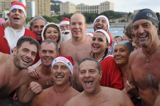Eine Gruppe fröhlicher Menschen, einige mit Weihnachtsmützen, baden im Meer.