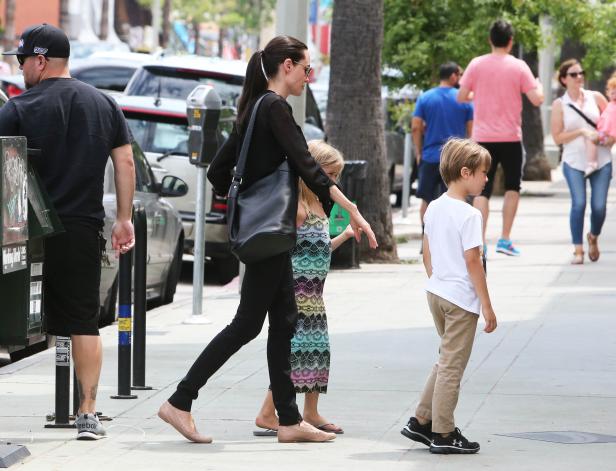 Angelina Jolie geht mit ihren Kindern auf dem Bürgersteig entlang.