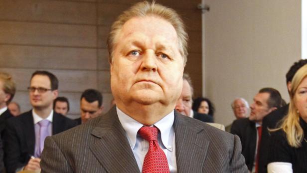 Ein Mann mit Anzug und roter Krawatte sitzt im Publikum.