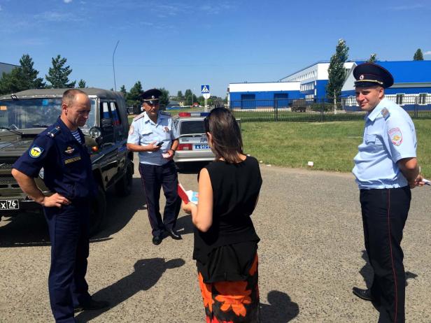 Drei Polizisten sprechen mit einer Frau auf einer Straße.