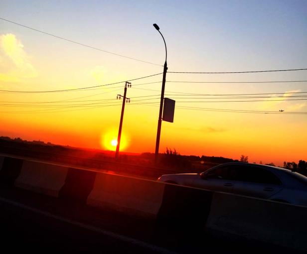 Ein Auto fährt auf einer Straße bei Sonnenuntergang.