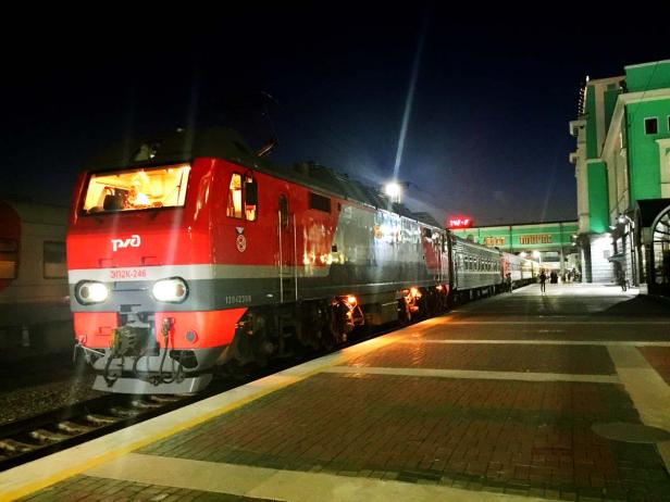 Ein roter russischer Zug steht nachts an einem Bahnsteig.