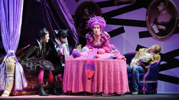 Antonia und der Reißteufel in der Volksoper… Eine Theaterszene mit extravagant gekleideten Darstellern und farbenfroher Bühnengestaltung.