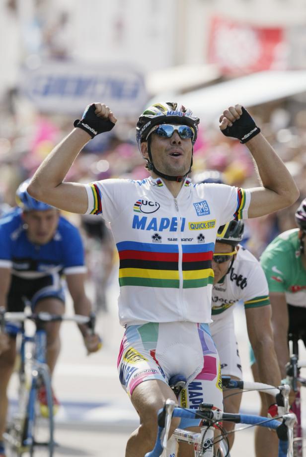 Ein Radrennfahrer im Mapei-Trikot jubelt mit erhobenen Armen.