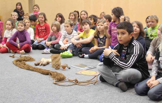 Eine Gruppe von Kindern sitzt im Kreis um einige geflochtene Gegenstände.