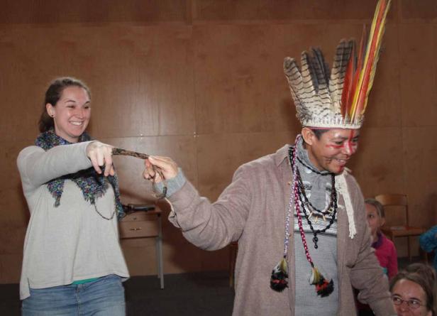Eine Frau hält ein Seil, das von einem Mann mit Kopfschmuck und Gesichtsbemalung gehalten wird.