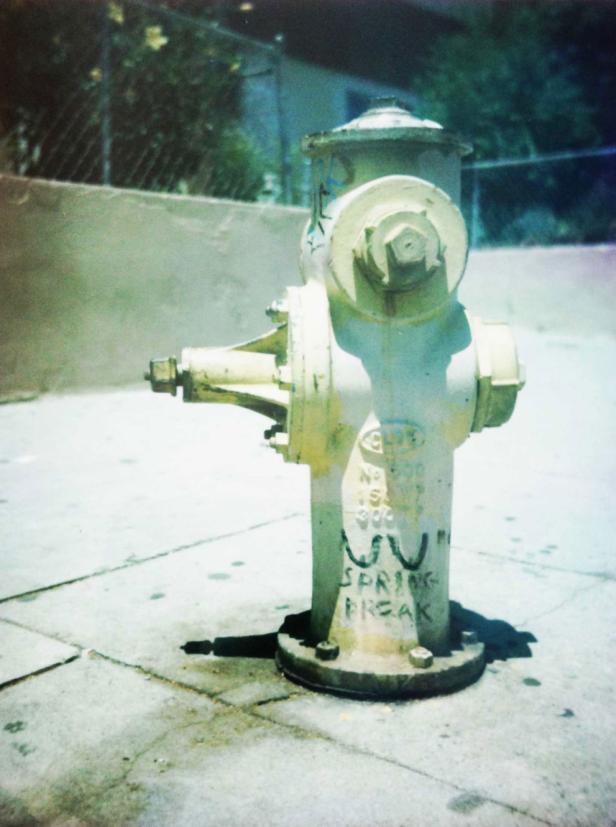 Ein gelber Hydrant mit Graffiti steht auf einem Bürgersteig.