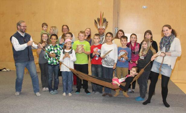 Eine Gruppe von Kindern und Erwachsenen posiert mit einer Hängematte und Requisiten für ein Foto.