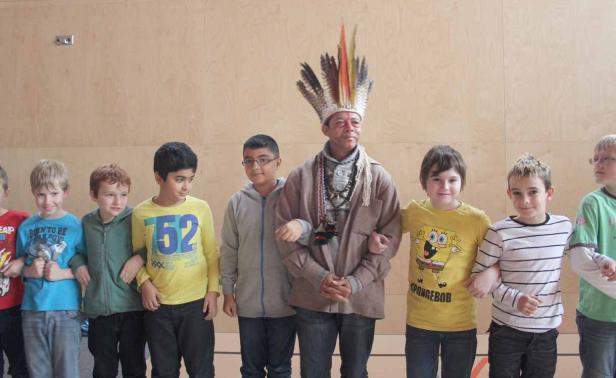 Eine Gruppe von Jungen steht mit einem Mann mit Federschmuck zusammen.