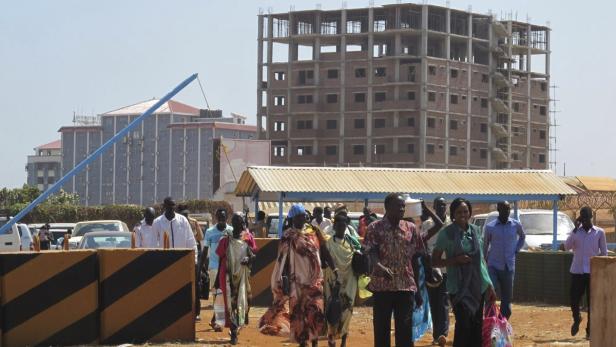 Eine Gruppe von Menschen geht vor einem unfertigen Gebäude entlang.