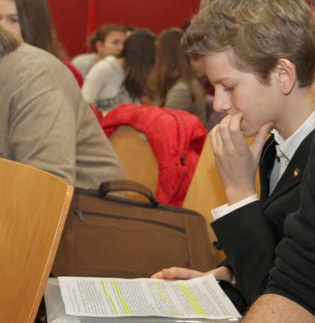 Ein junger Mann in einem Anzug liest ein Dokument mit Markierungen.