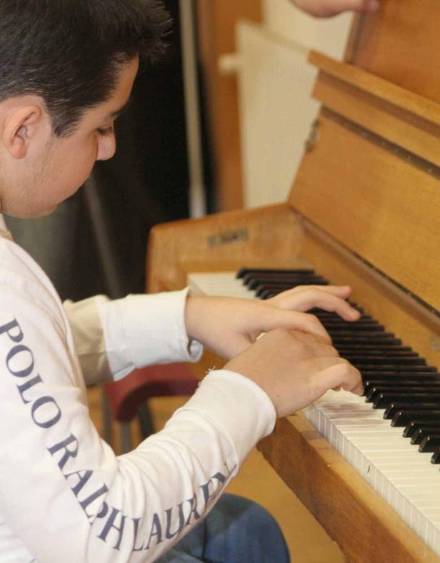 Ein junger Mann spielt auf einem hellen Klavier.