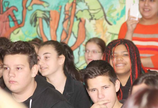Eine Gruppe von Jugendlichen steht vor einem bunten Wandbild.