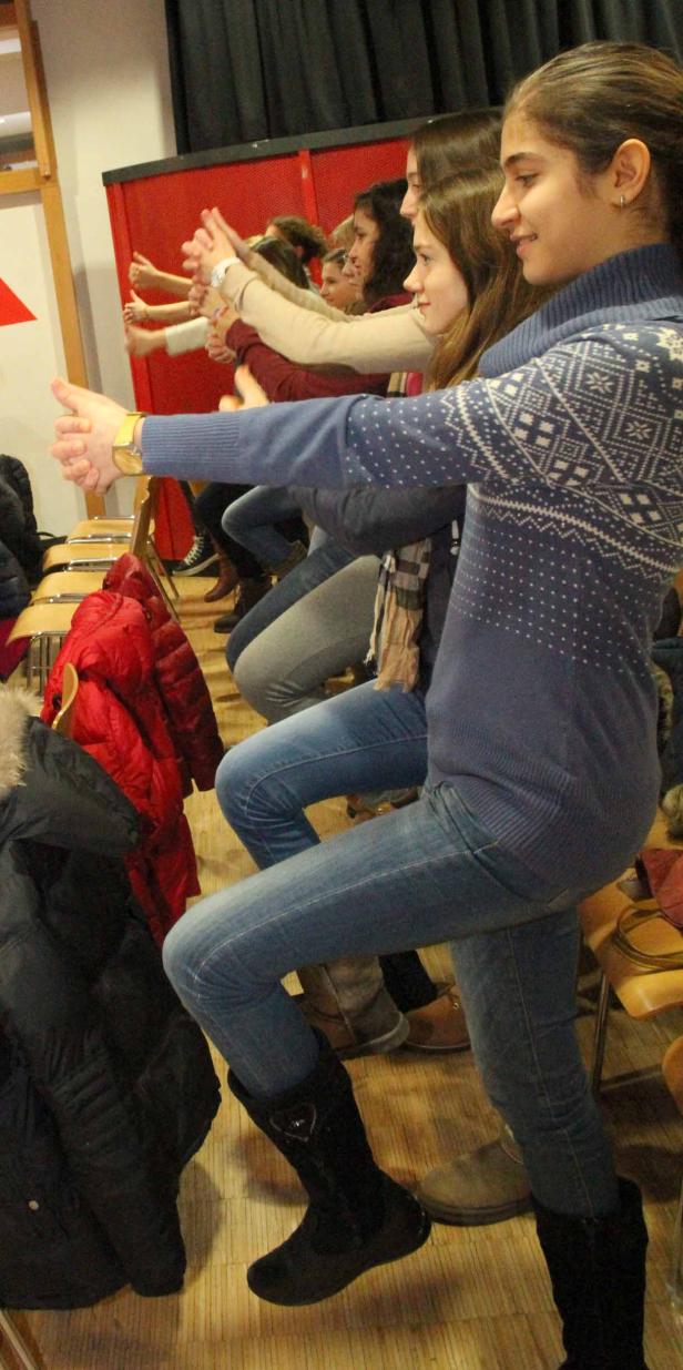 Eine Gruppe junger Frauen sitzt auf Stühlen und streckt die Daumen nach oben.