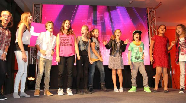 Eine Gruppe von Kindern steht auf einer Bühne und singt.