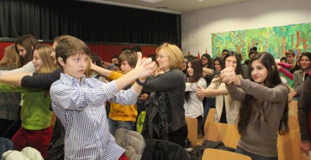 Eine Gruppe von Menschen steht in einem Raum und streckt die Arme nach vorne.