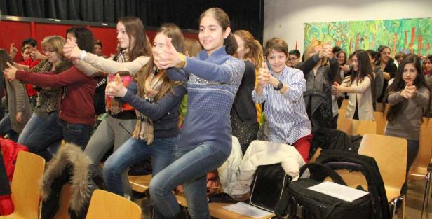 Eine Gruppe Jugendlicher steht in einem Raum und ahmt mit ihren Händen Pistolen nach.