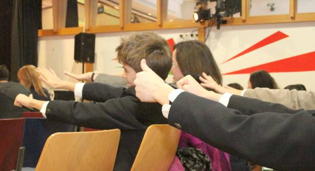 Eine Gruppe von Menschen streckt die Arme in einem Raum aus.