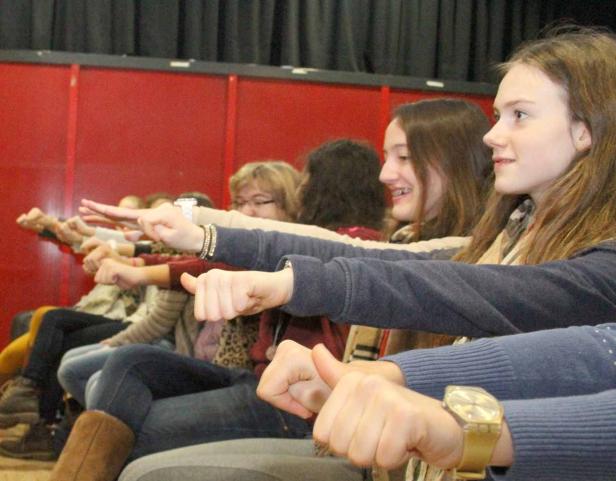 Eine Gruppe junger Leute sitzt und streckt die Fäuste nach vorne.