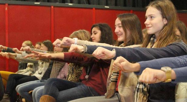 Eine Gruppe junger Frauen sitzt und streckt die Arme mit geballten Fäusten nach vorne.