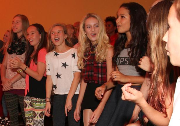 Eine Gruppe junger Frauen steht zusammen und singt oder jubelt.