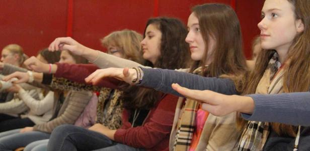 Eine Gruppe junger Frauen sitzt und streckt die Arme nach vorne.