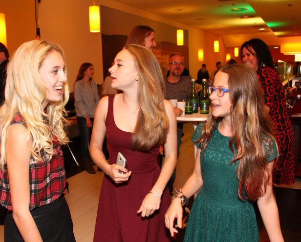 Drei junge Frauen unterhalten sich auf einer Party oder Veranstaltung.