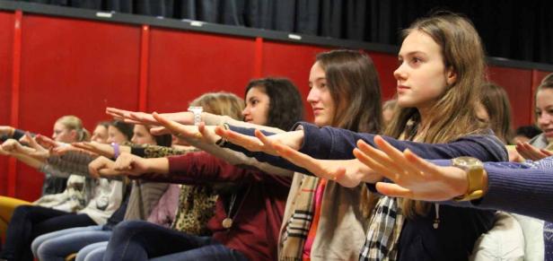 Eine Gruppe junger Frauen sitzt in einer Reihe und streckt die Arme nach vorne.