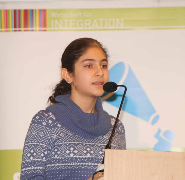Ein junges Mädchen spricht bei einer Veranstaltung zum Thema „Wirtschaft für Integration“.